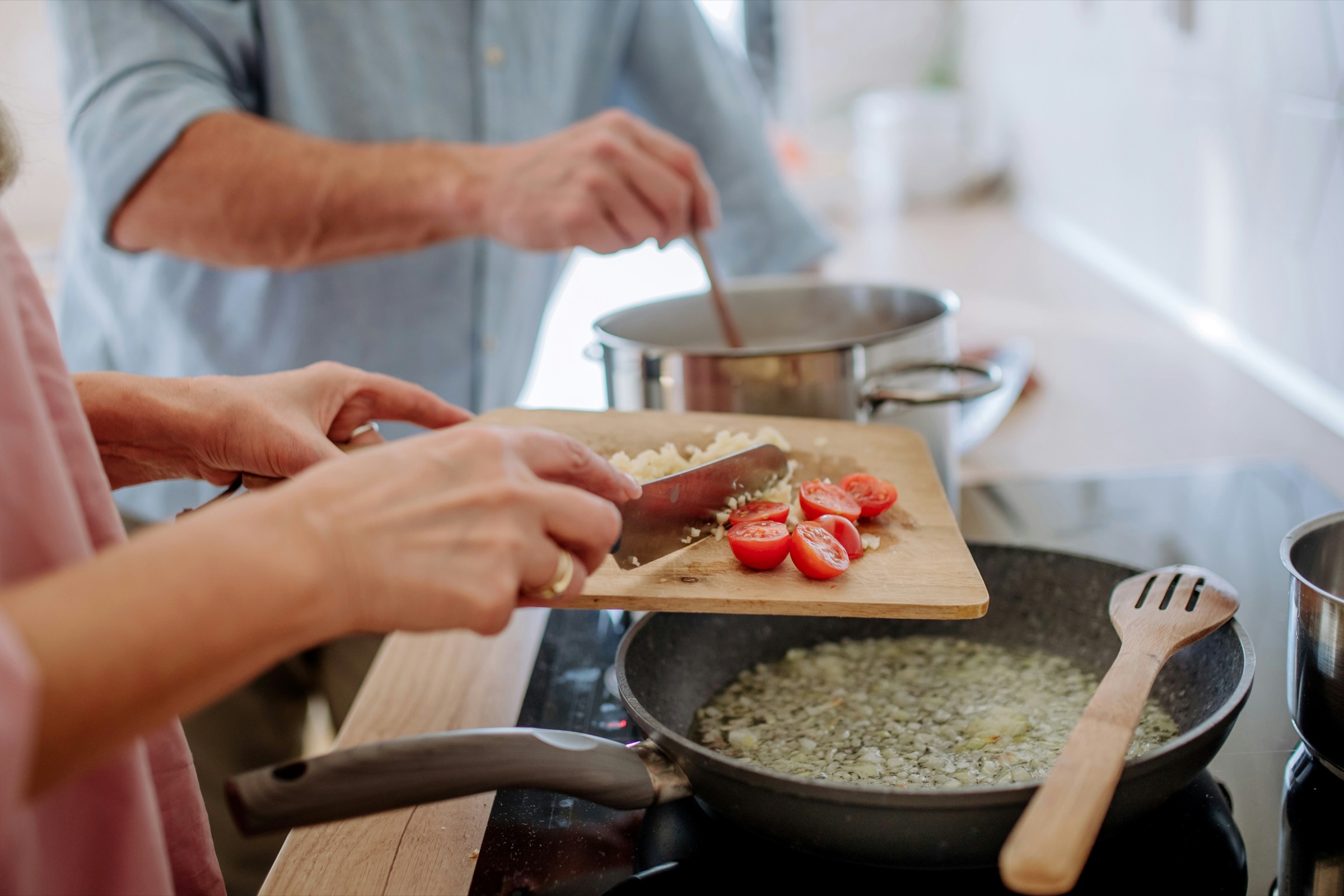 Two people preparing a meal with chopped ingredients in a bright home kitchen