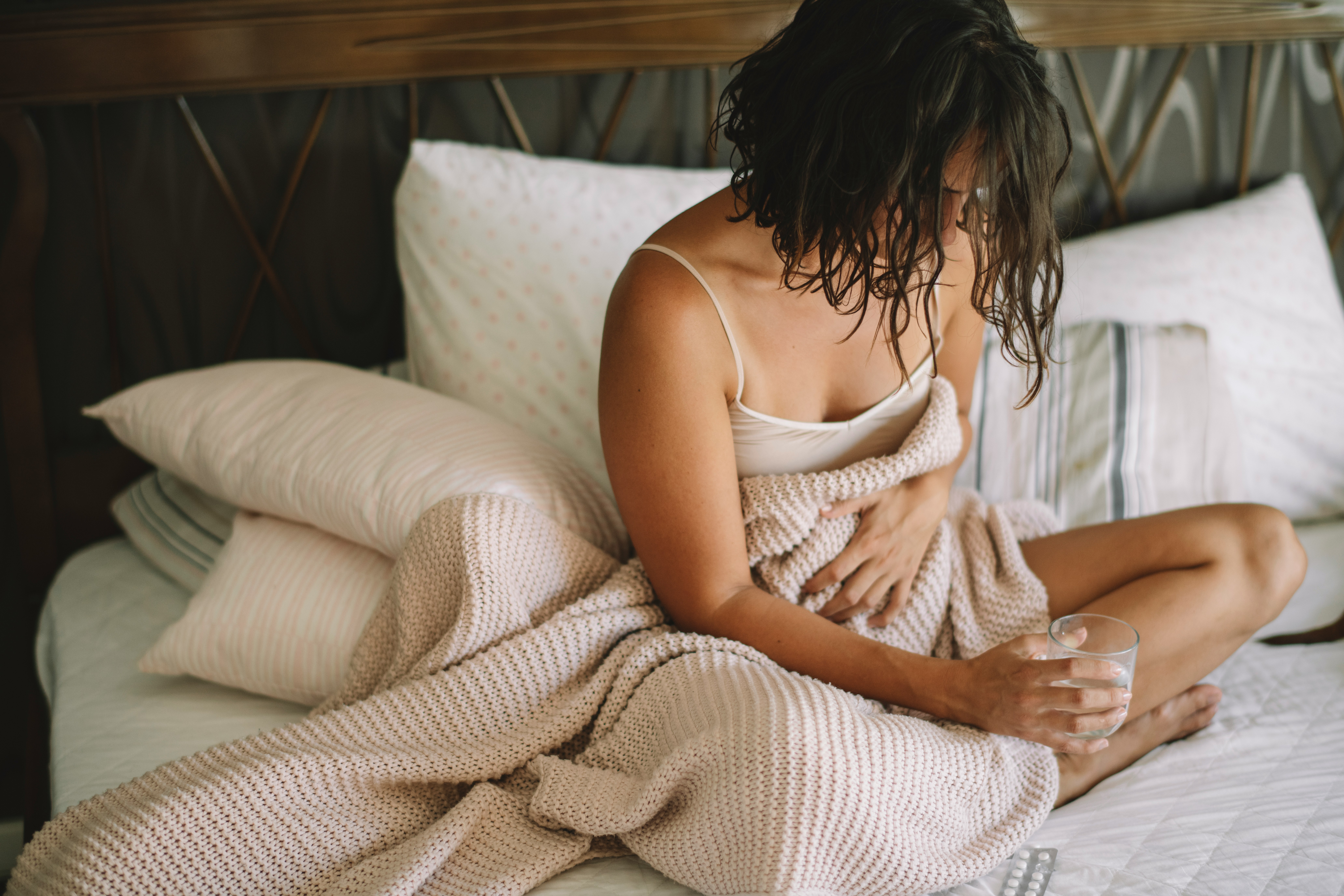 Person sitting up in bed with abdominal discomfort in the morning